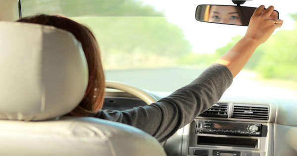 woman adjusting rear view mirror