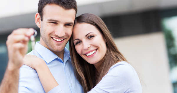 young couple holding keys to first home
