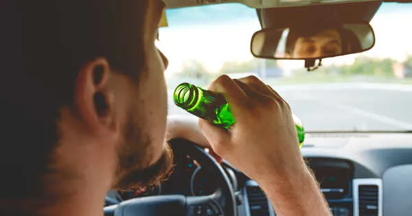 man driving drinking a bottle of beer