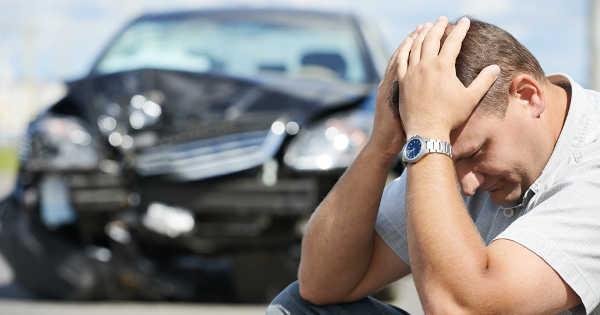 sad man in front of wrecked car