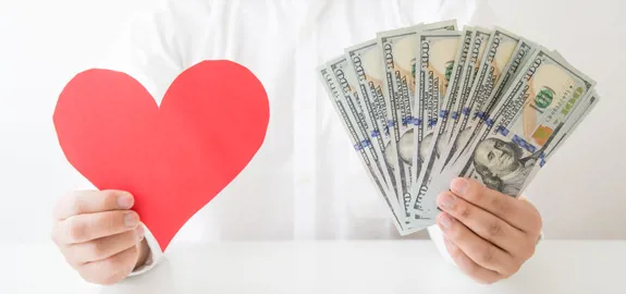 man holding cut-out paper heart and money