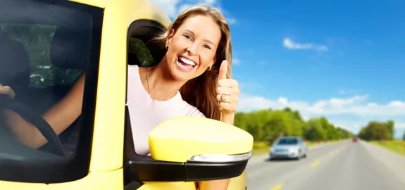 young driver leaning out car window giving thumbs up